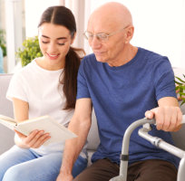 caregiver and senior man reading a book