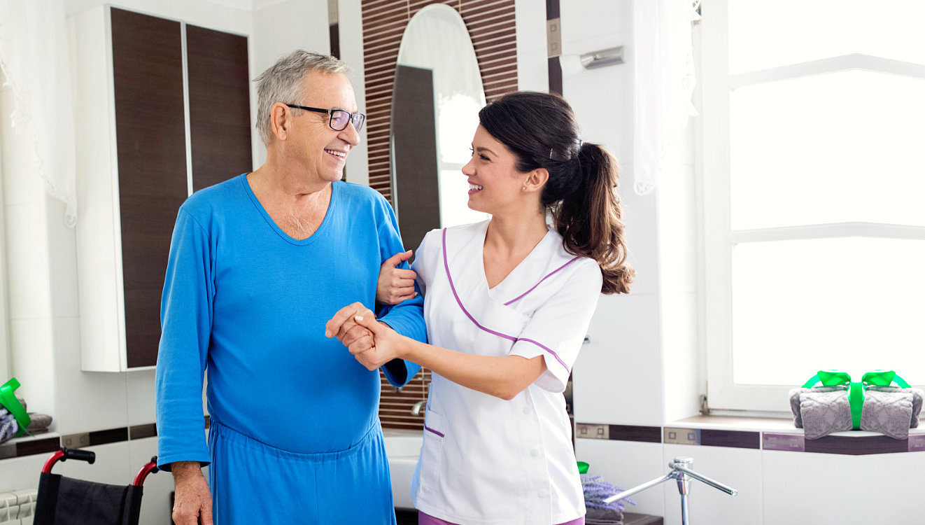 senior man and caregiver smiling at each other