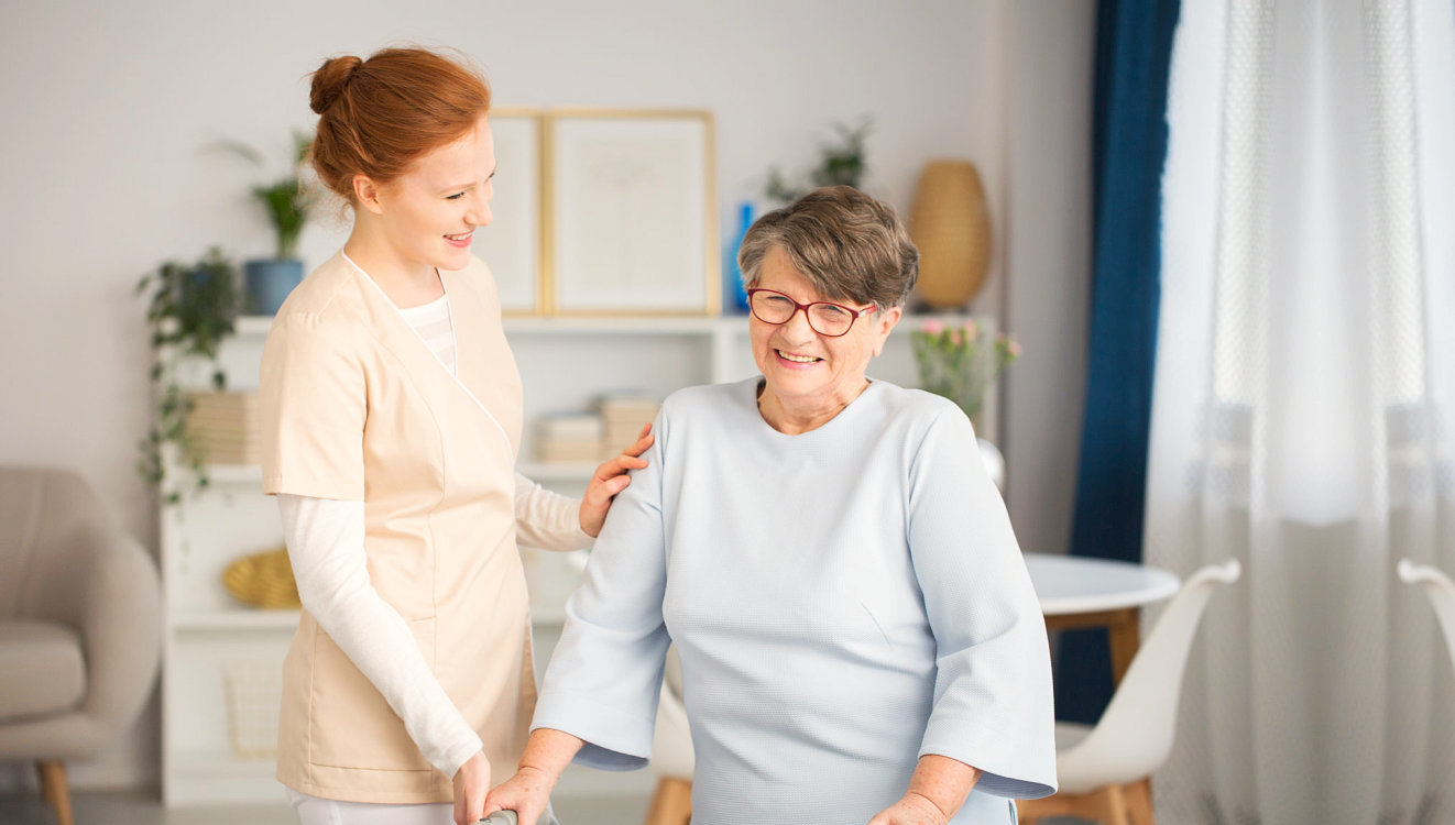 senior woman and caregiver smiling