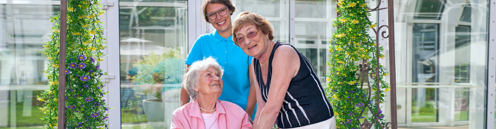 two senior woman with caregiver smiling